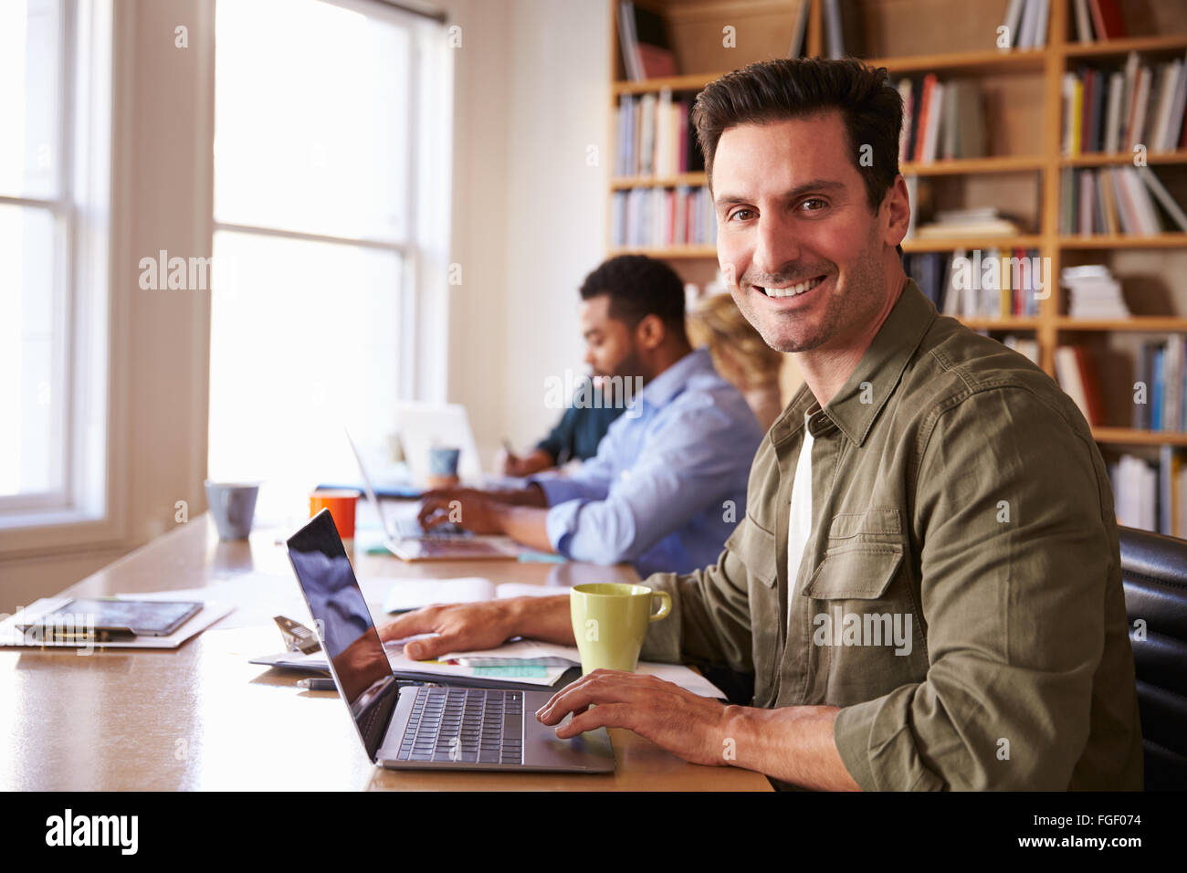 Businessman Using Laptop At Desk In Office Occupé Banque D'Images