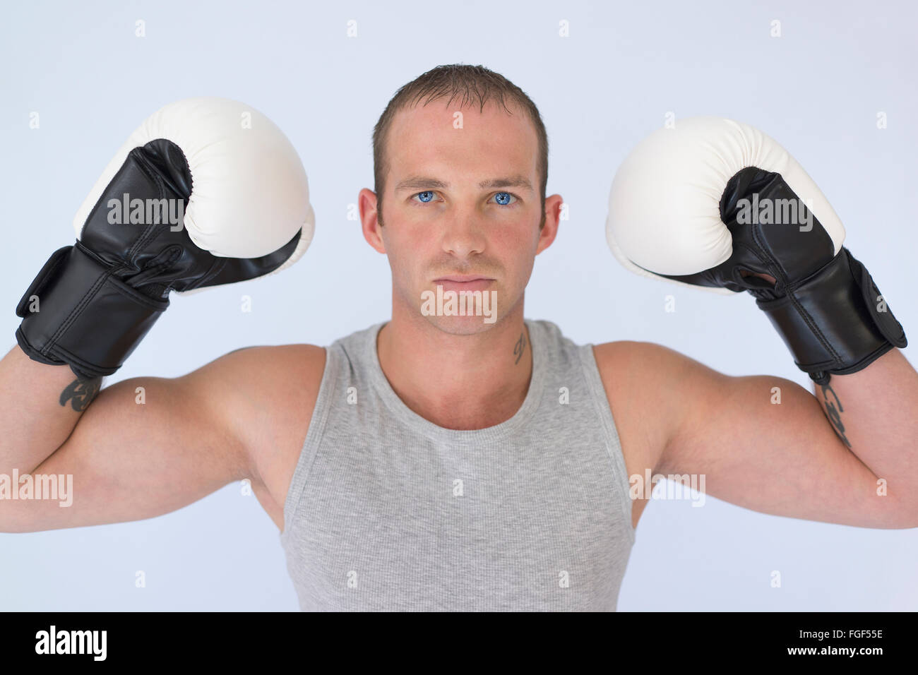 Homme portant des gants de boxe fléchissant ses biceps avec un air sérieux de concentration Banque D'Images