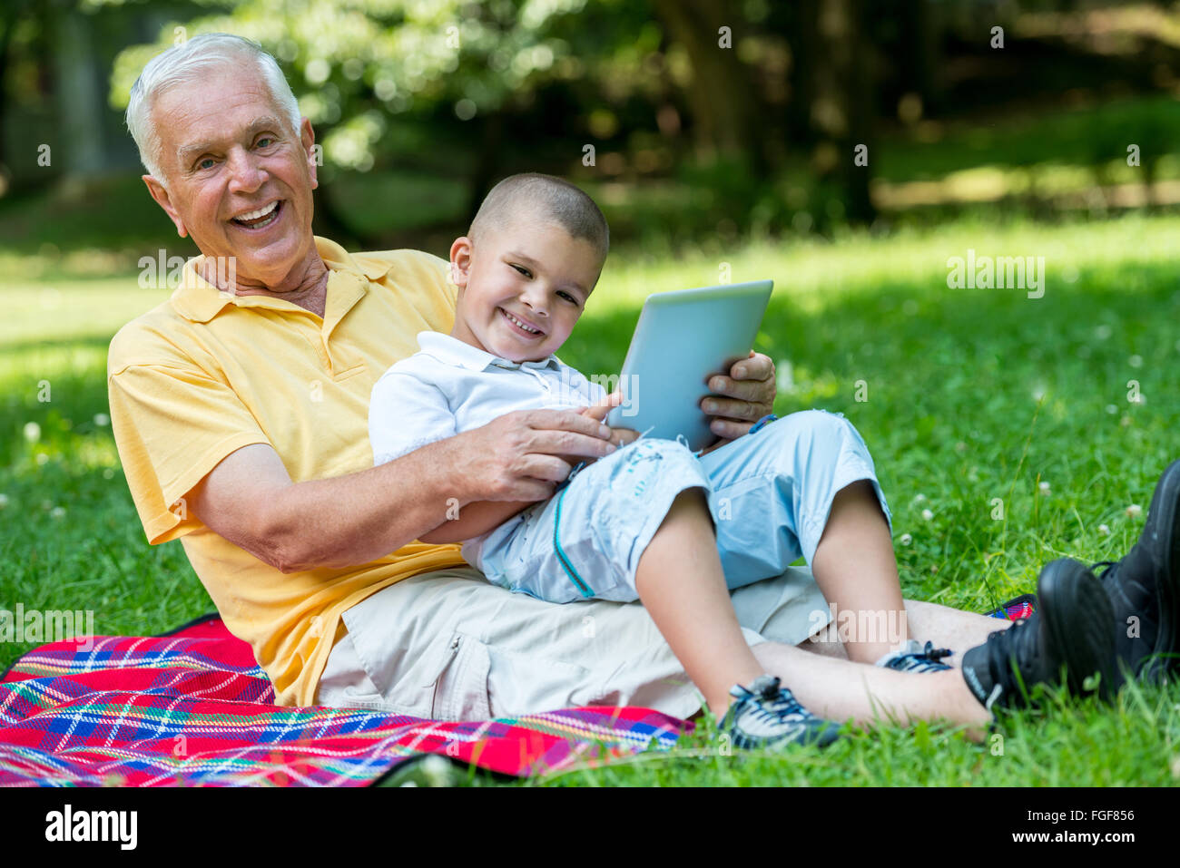 Grand-père et enfant de park en utilisant tablet Banque D'Images