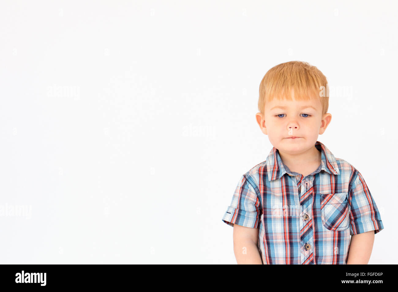 Portrait d'un jeune garçon debout sur un fond blanc. Banque D'Images