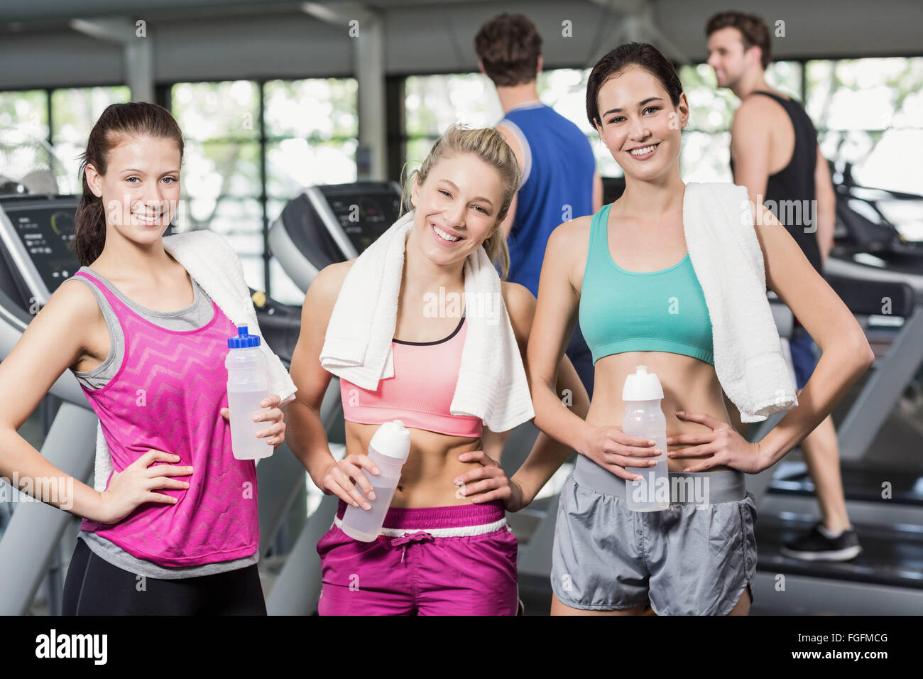 Athletic smiling women posant avec une bouteille d'eau Banque D'Images