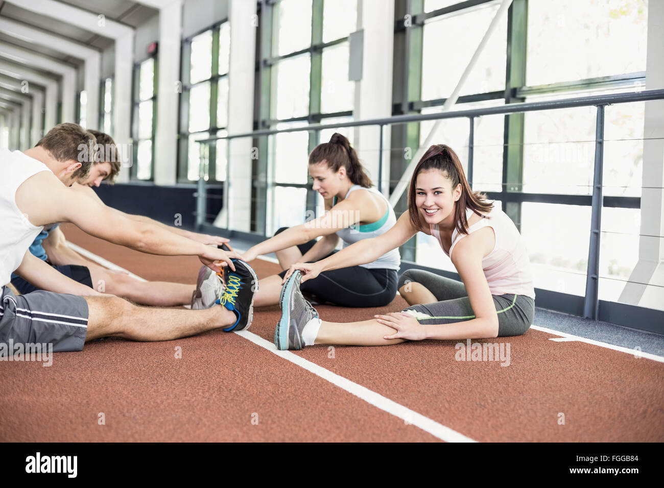 Quatre hommes et femmes s'étendant d'athlétisme Banque D'Images