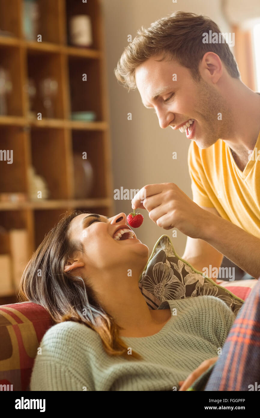 Jeune couple de câlins sur le canapé sous couverture Banque D'Images