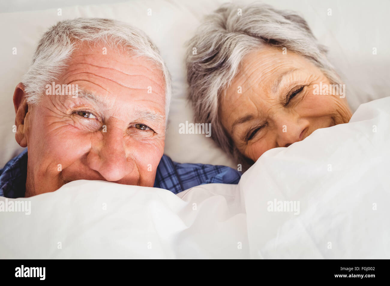 Happy senior couple smiling in bed Banque D'Images