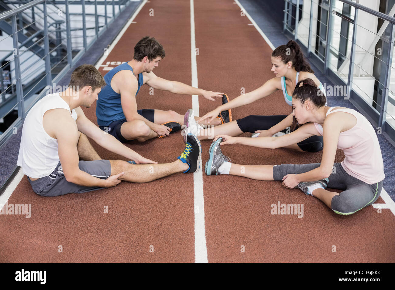 Quatre hommes et femmes s'étendant d'athlétisme Banque D'Images