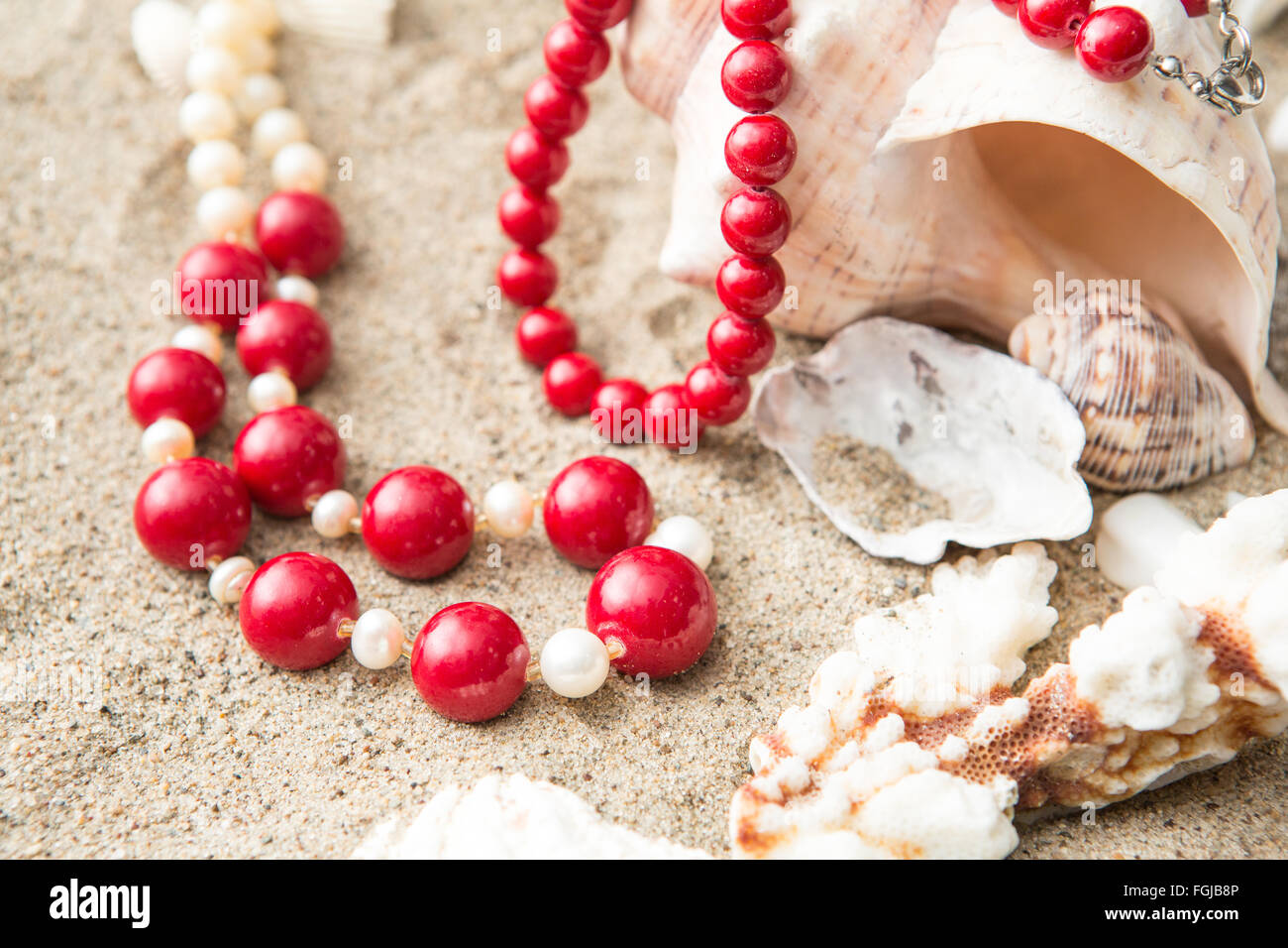 Les coquillages et collier rouge sur le sable à la plage Banque D'Images