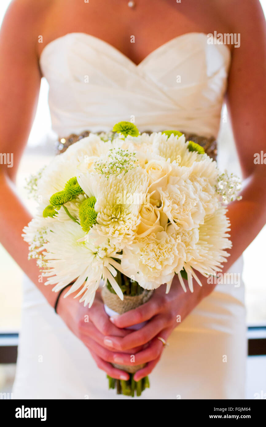 Bouquet floral blanc dans les mains d'une mariée le jour de son mariage avec beaucoup de décorations de fleurs. Banque D'Images