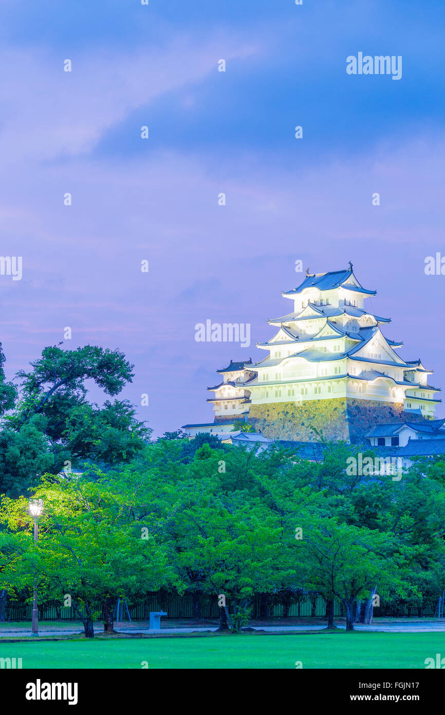 Himeji-jo Château courts au coucher du soleil avec deep purple sky et de l'avant-plan les arbres de parc à proximité de Himeji, Japon après 201 Banque D'Images