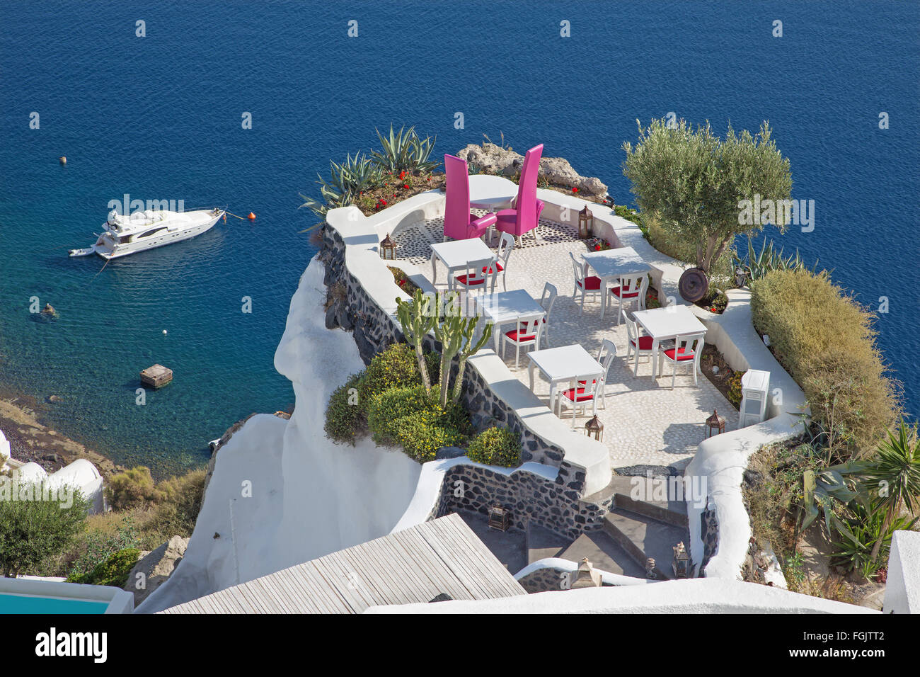 Santorin - Le restaurant mariage à dîner romantique à Oia (Ia) et le yacht sous des falaises à l'arrière-plan. Banque D'Images