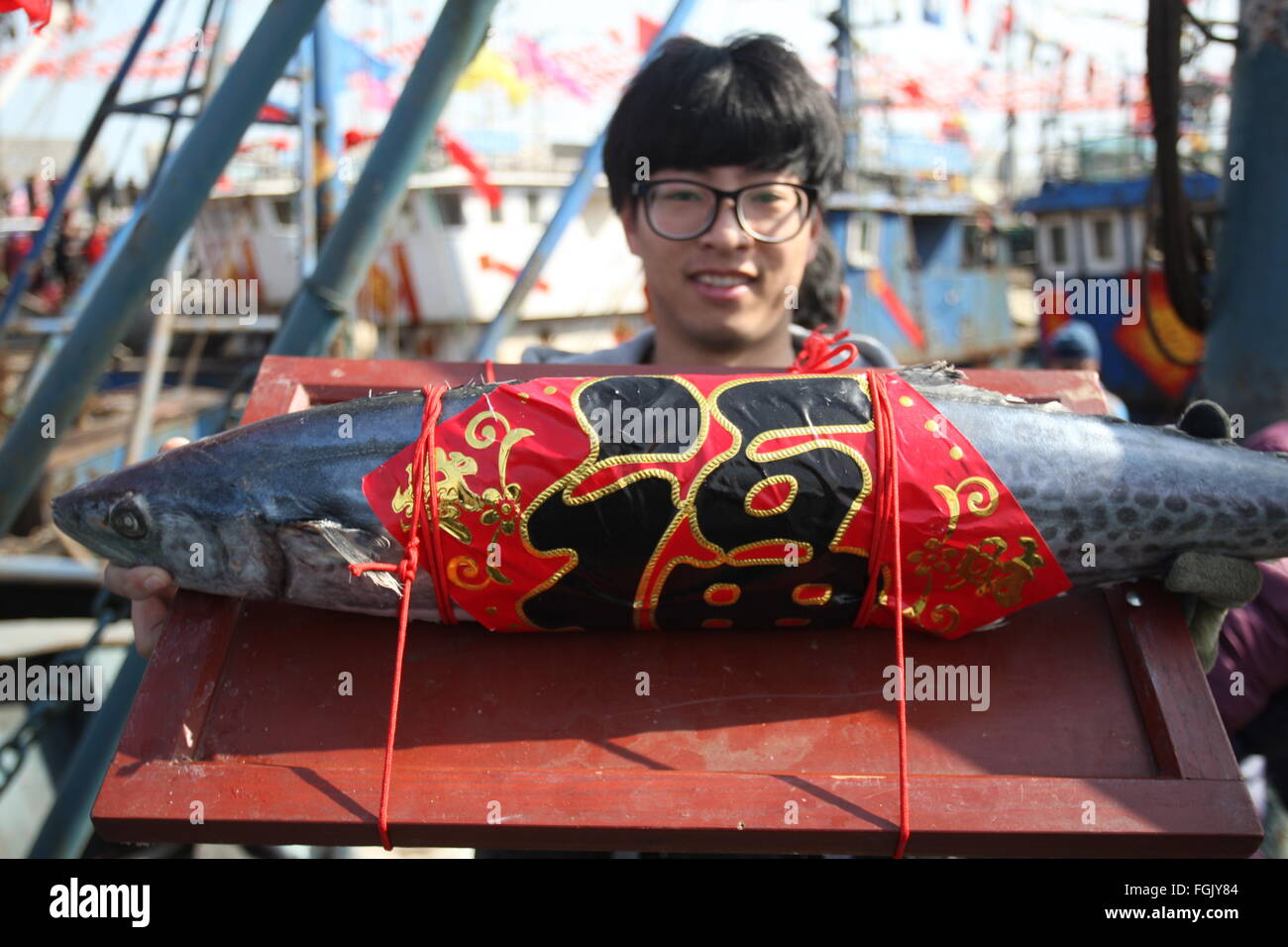 Yantai, Chine, la province de Shandong. Feb 20, 2016. Un homme présente un poisson comme offrande sacrificielle pour assister à la pêche locale Fête des lanternes, un rituel adorant les dieux de la mer et en priant pour la récolte de l'année prochaine, à un port de pêche à Yantai, province du Shandong en Chine de l'Est, le 20 février 2016. Credit : Shen Jizhong/Xinhua/Alamy Live News Banque D'Images