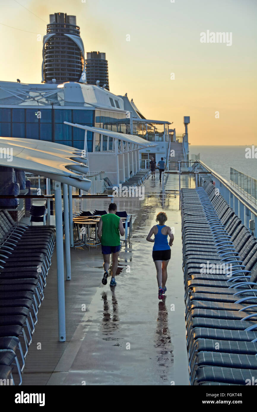 Pont de bateau de croisière d'exécution joggers tôt le matin avec soin le long circuit dédié entre transats après une nuit de pluie en mer Méditerranée Banque D'Images