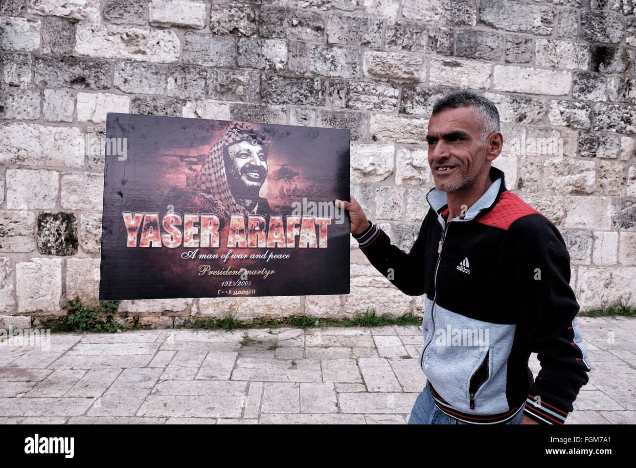 Un palestinien est titulaire d'une affiche portant la figure de l'ancien dirigeant palestinien Yasser Arafat à l'extérieur de la porte de Damas à Jérusalem-Est Israël Banque D'Images