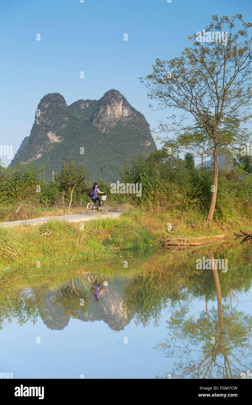 Femme à vélo le long de la rivière Yulong, Yangshuo, Guangxi, Chine Banque D'Images