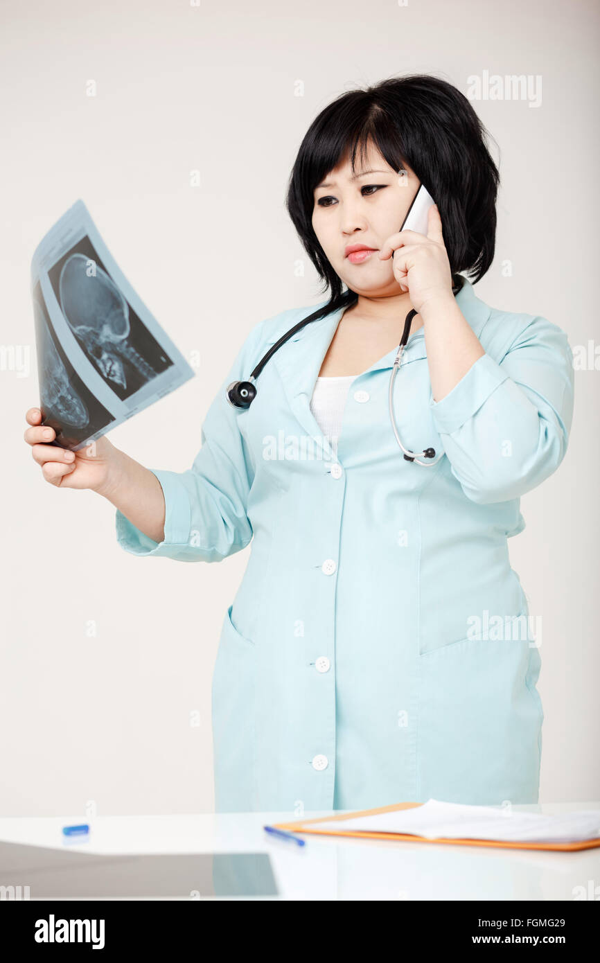 Femme médecin asiatique robe en discutant de diagnostic, en considérant X-ray photo. Erreur médicale, la commission médicale. Banque D'Images