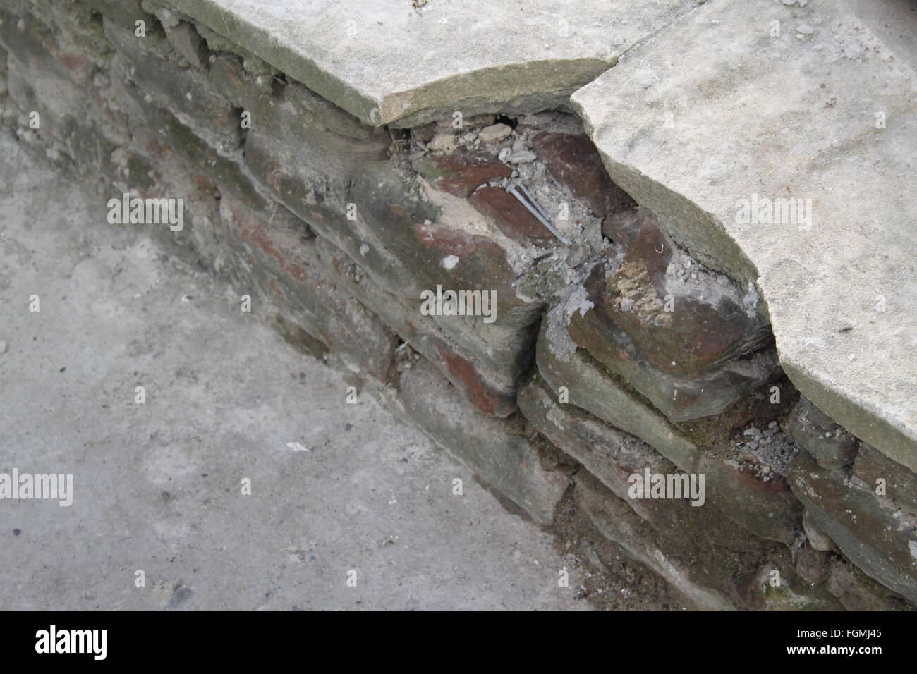 Pièces de béton brisées sur le haut d'un mur de grès rouge, en ruine Banque D'Images