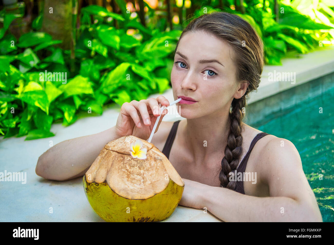 Jeune femme dans une piscine avec une noix de coco fraîche Banque D'Images