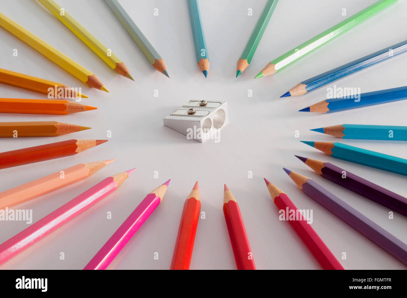 Crayons de couleur autour d'un air menaçant un taille-crayon. Banque D'Images