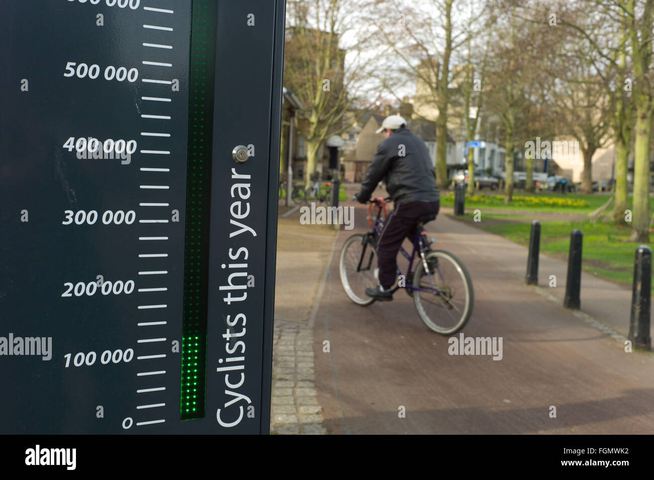 Cycliste passant un signe à Cambridge UK qui montre le nombre de cyclistes qui ont utilisé la voie du cycle de l'année Banque D'Images