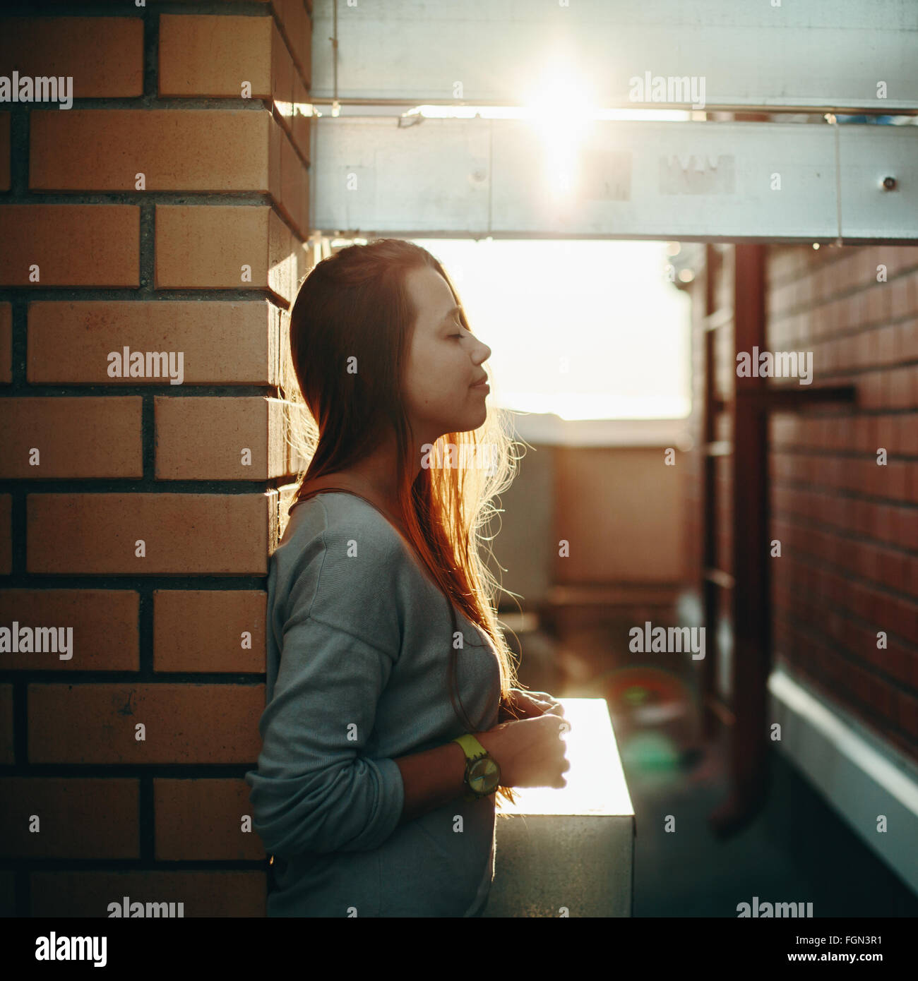 Jeune femme debout sur une rue avec les yeux fermés dans le coucher du soleil la lumière. Selective Focus, des reflets. Banque D'Images