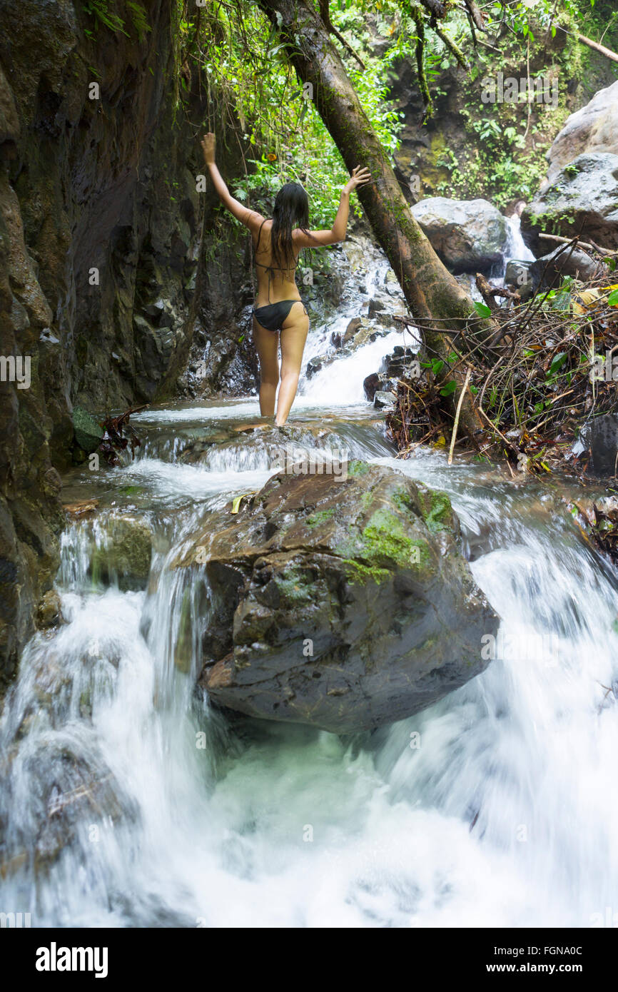 L'Amérique centrale, le Costa Rica, Golfito, une jeune femme l'ascension d'une cascade d'eau de montagne dans la forêt tropicale à Playa Nicuesa Banque D'Images