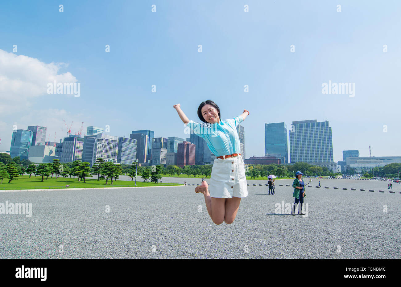 Tokyo Japon saut de touristes chinois à l'air à l'Imperial Gardens avec ville en arrière-plan, M. Parution Modèle-4 Banque D'Images