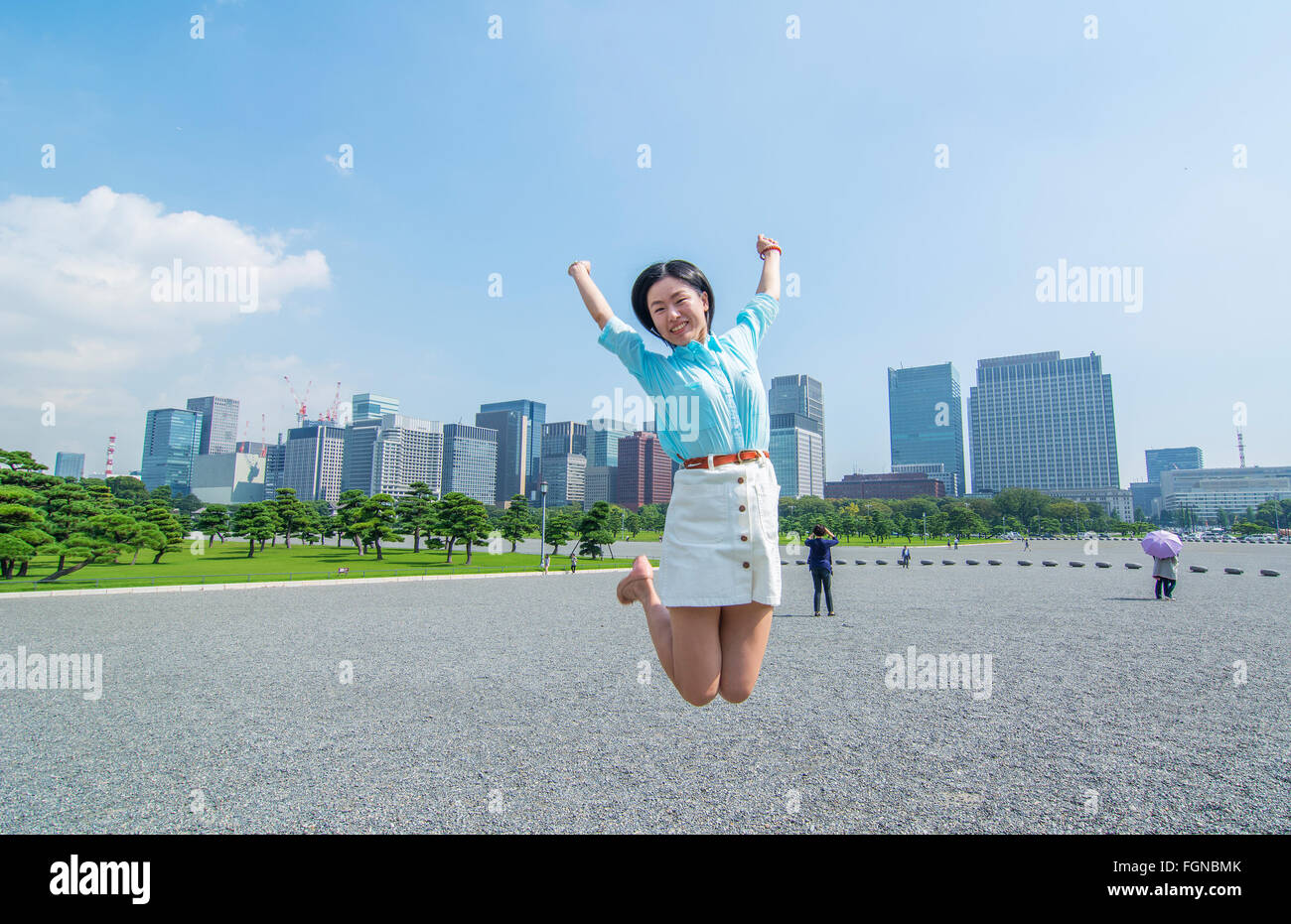 Tokyo Japon saut de touristes chinois à l'air à l'Imperial Gardens avec ville en arrière-plan, M. Parution Modèle-4 Banque D'Images