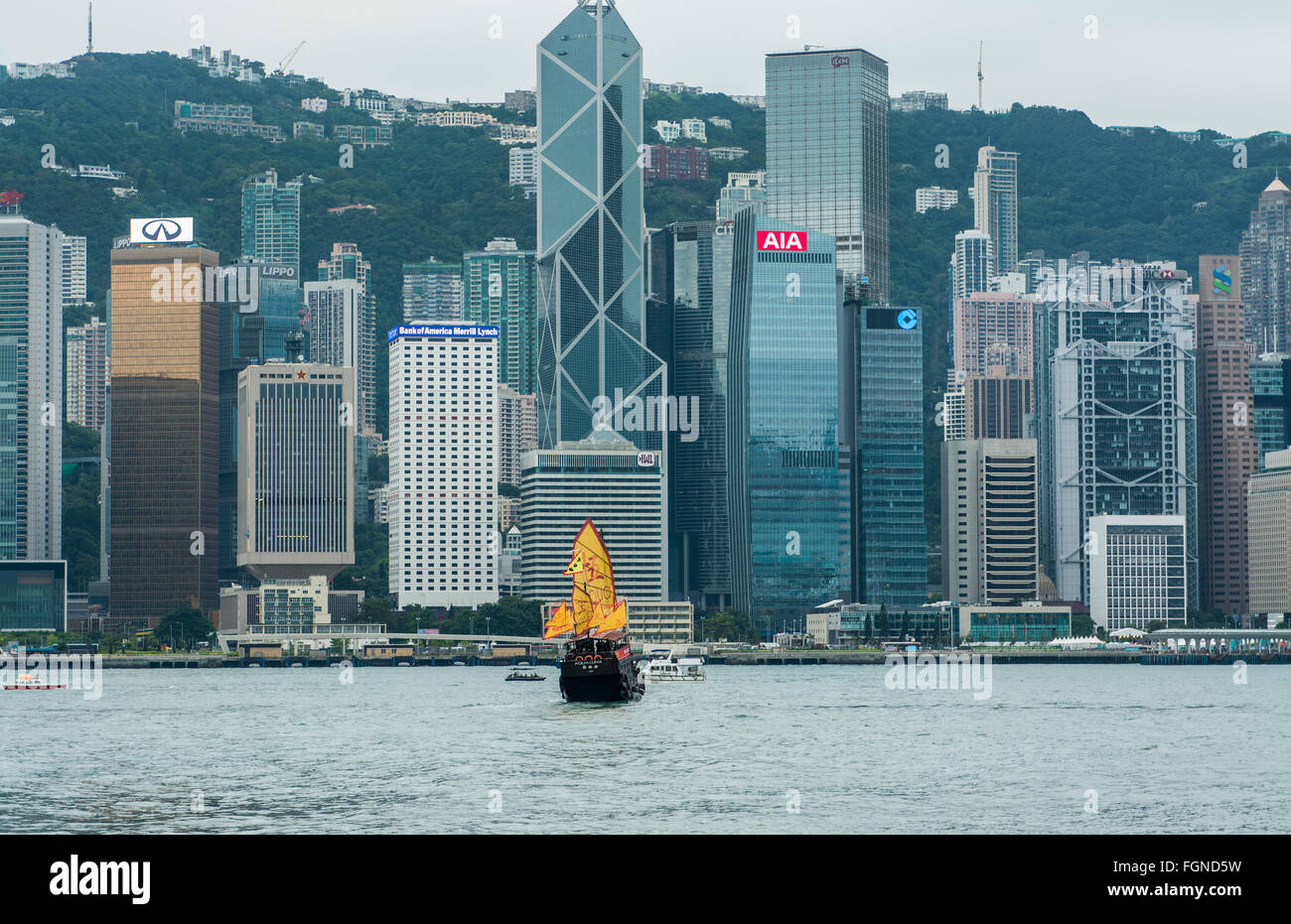 Chine Hong Kong skyline à partir de l'eau avec jonque traditionnelle avec advertiosing isc jaune contre l'arrière-plan de la ville Banque D'Images