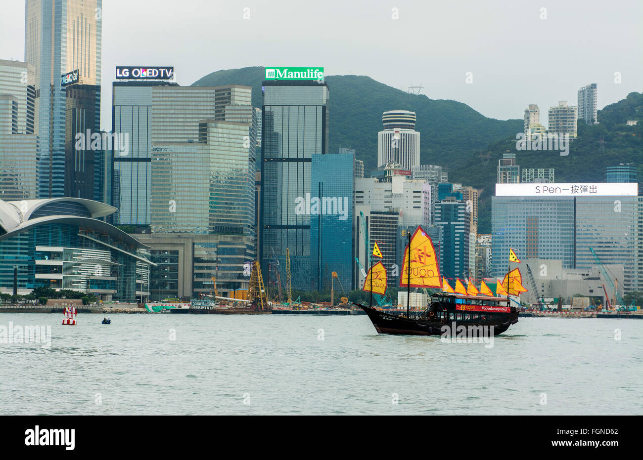 Chine Hong Kong skyline à partir de l'eau avec jonque traditionnelle avec advertiosing isc jaune contre l'arrière-plan de la ville Banque D'Images