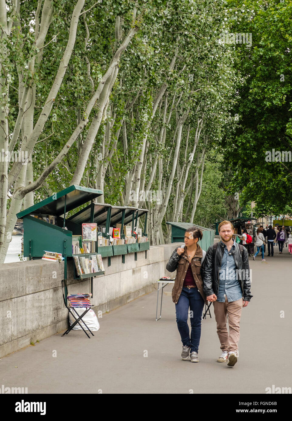 Un couple marche par livre-stands qu'une ligne de la rue Paris, à côté de la rivière Seine Banque D'Images