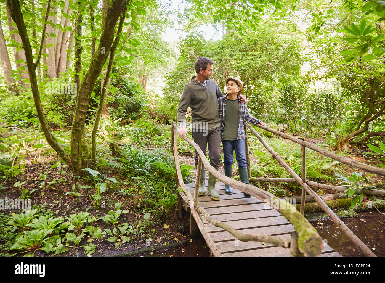 Père et fils traversant la passerelle en forêt Banque D'Images