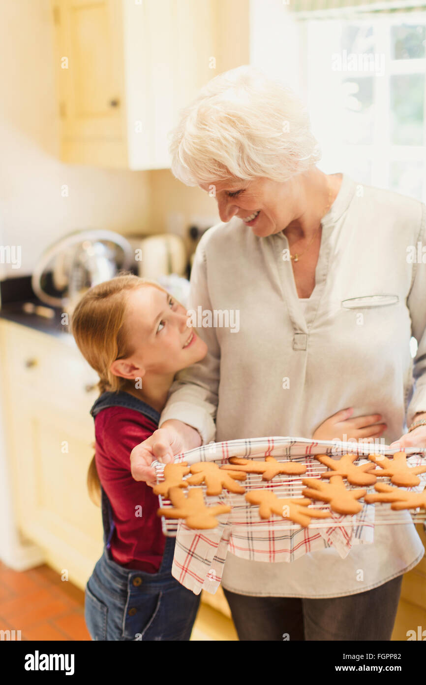 Granddaughter hugging grand-mère baking gingerbread cookies Banque D'Images