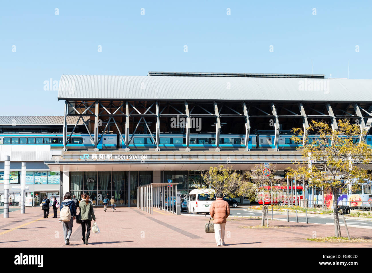 JR Kochi city station moderne au Japon. Premier plan, taxi, location de pickup et Tosaden Kotsu streetcar de tram. Ciel bleu, soleil éclatant. Banque D'Images