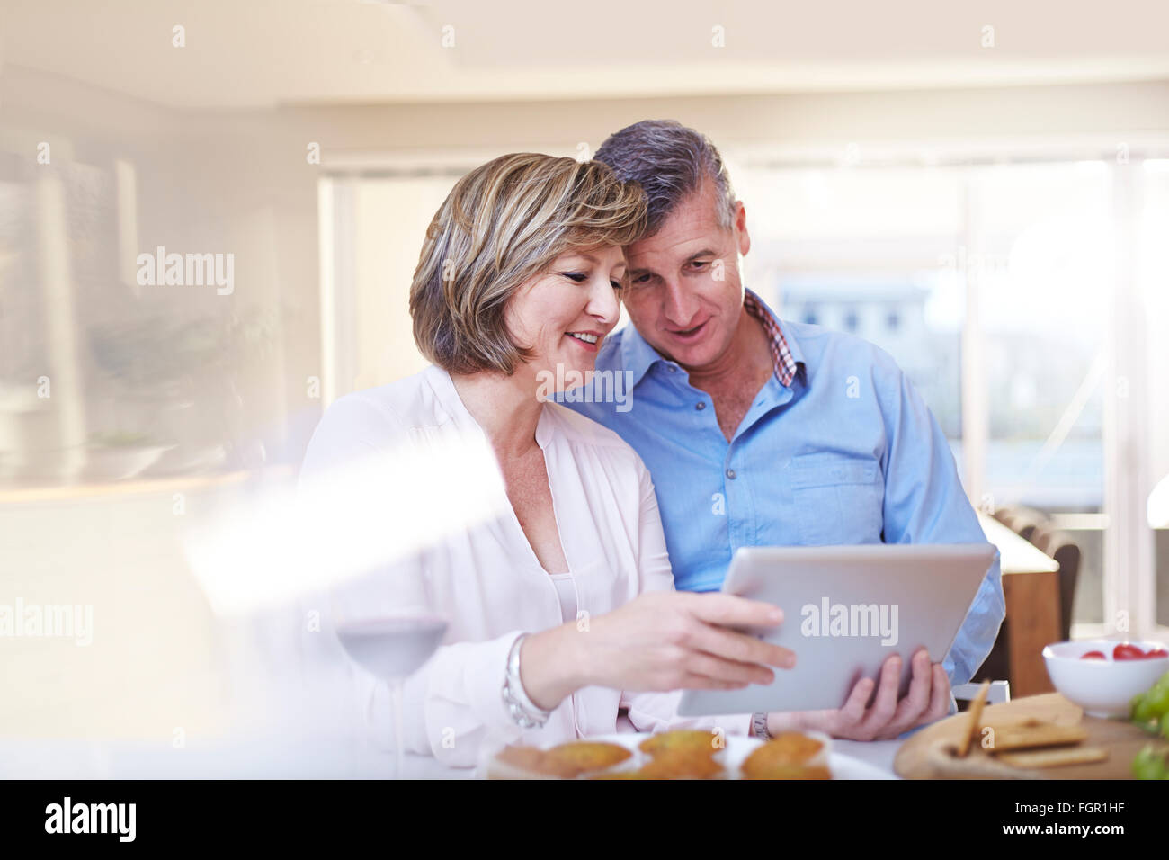 Couple using digital tablet in kitchen Banque D'Images