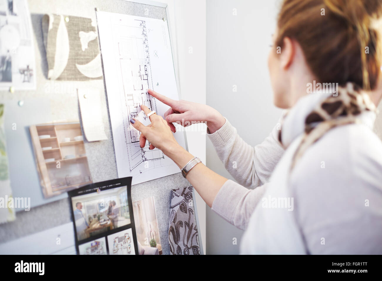 Les designers d'intérieur discussing blueprints hanging in office Banque D'Images