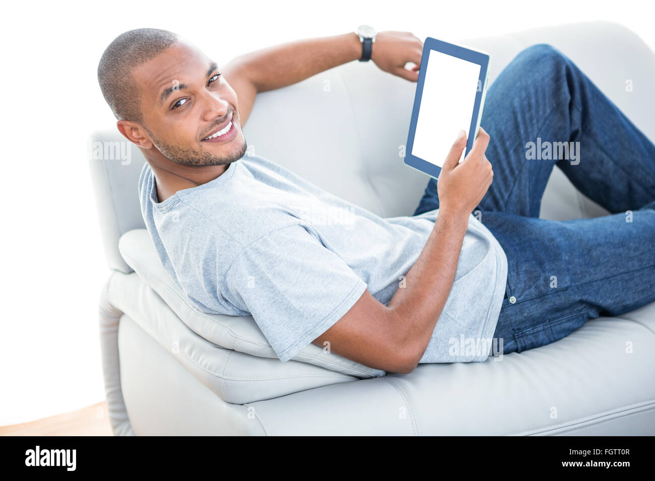 Portrait de jeune homme avec tablette sur canapé Banque D'Images