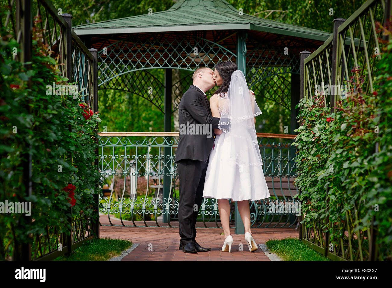 Bride and Groom kissing près de la gloriette dans le parc Banque D'Images