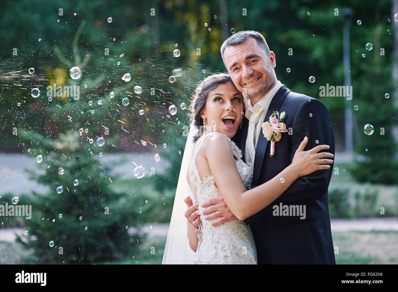 Heureux mariés et blowing bubbles in park Banque D'Images
