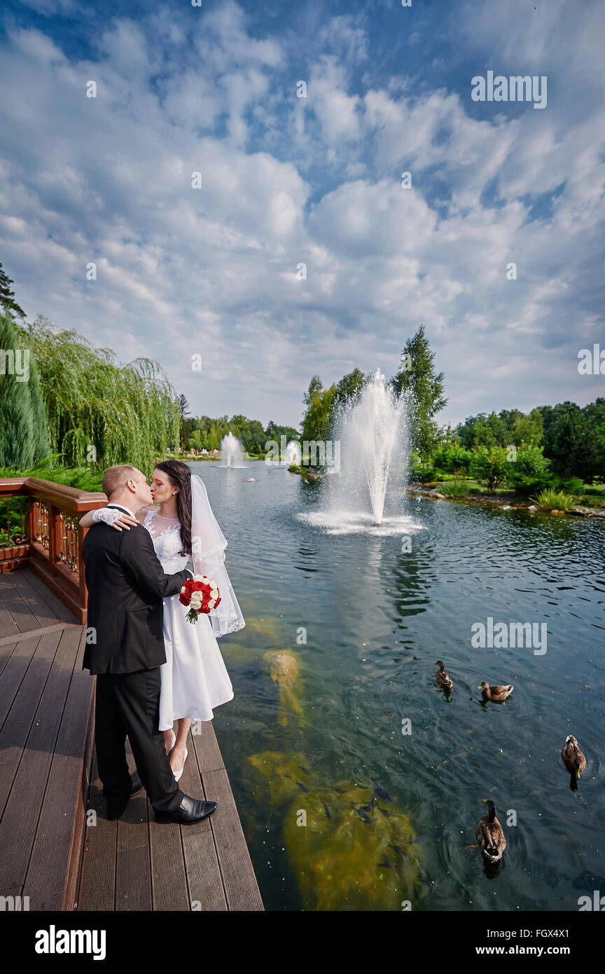 Belle brune et élégante mariée le marié élégant avec des sentiments vrais près d'un lac ensoleillé Banque D'Images