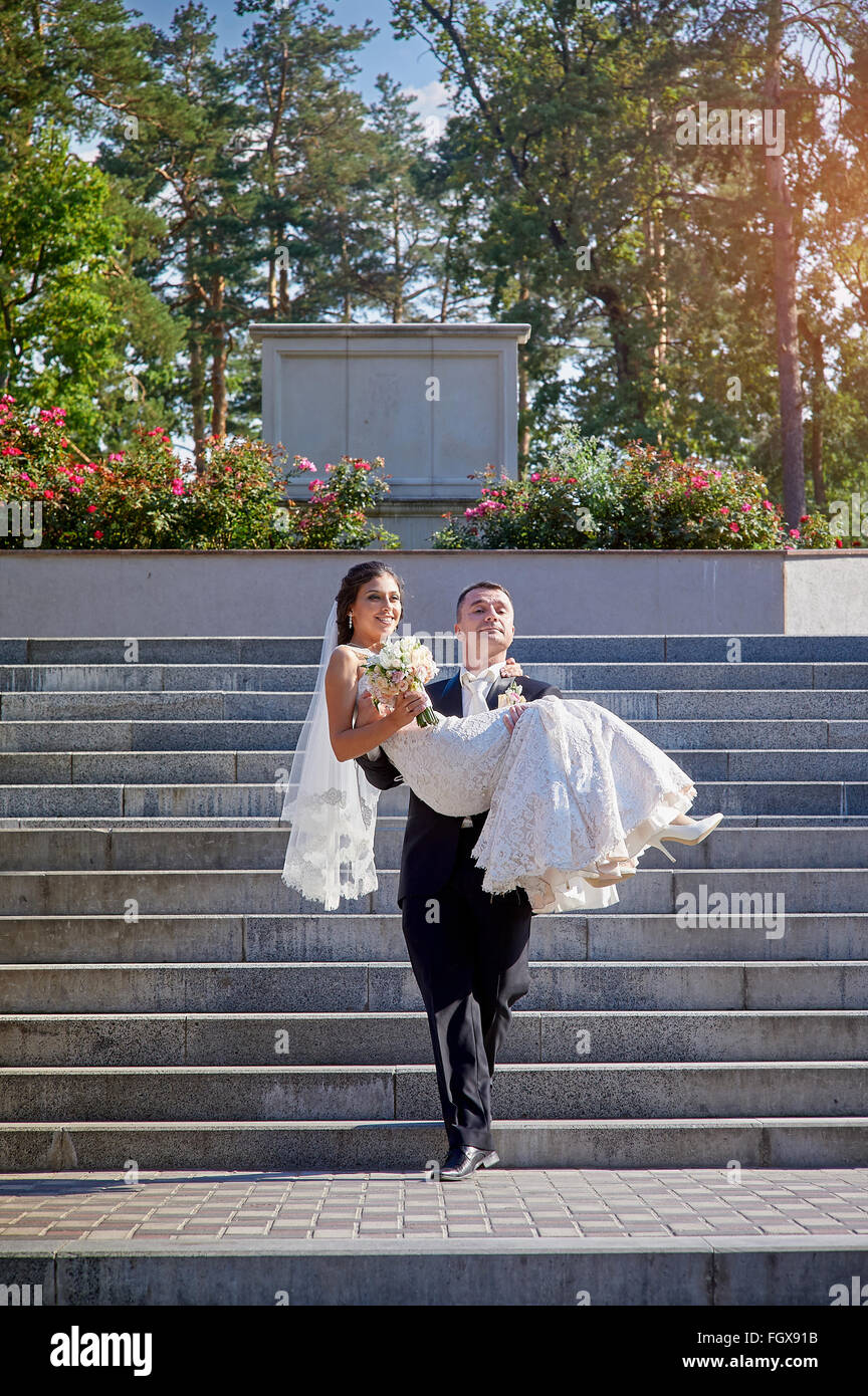 Le marié porte sa mariée dans ses bras dans l'escalier Banque D'Images