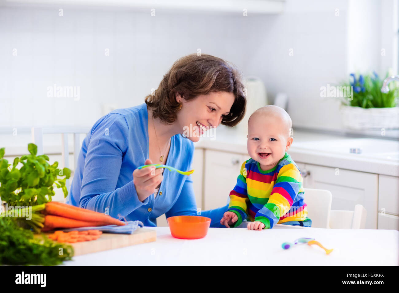 L'alimentation de la mère enfant. Premier aliment solide pour jeune enfant. Produits frais bio légumes carotte pour le déjeuner. Le sevrage de bébé. La maman et le petit garçon Banque D'Images