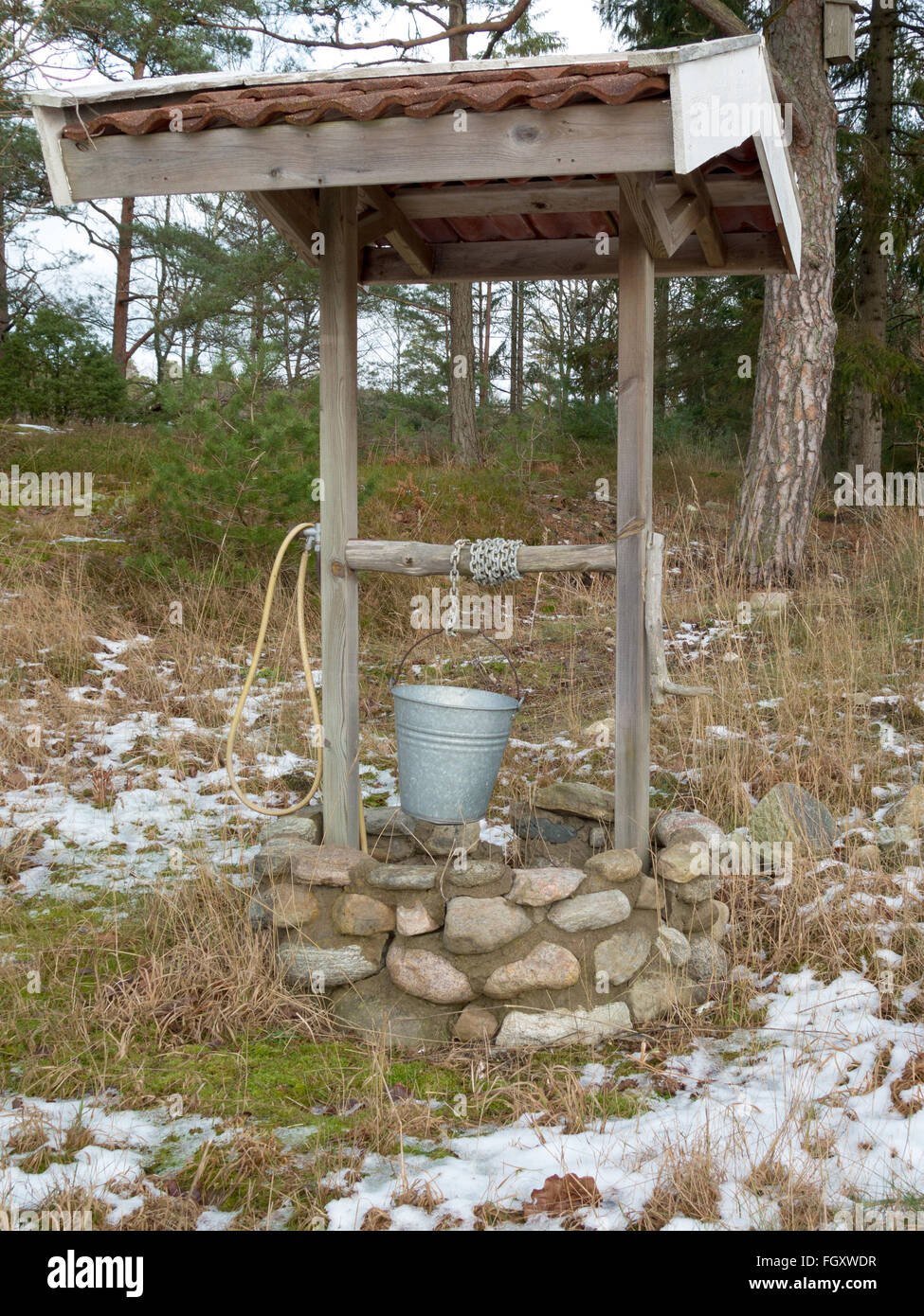 Un vieux puits dans la forêt avec une chaîne et une gamme d'eau Banque D'Images