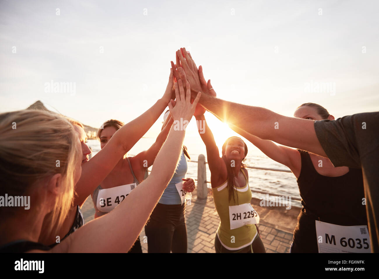 L'équipe d'athlétisme avec leurs mains empilées ensemble célébrer la réussite. Les coureurs de marathon, offrant un rapport 5. Banque D'Images