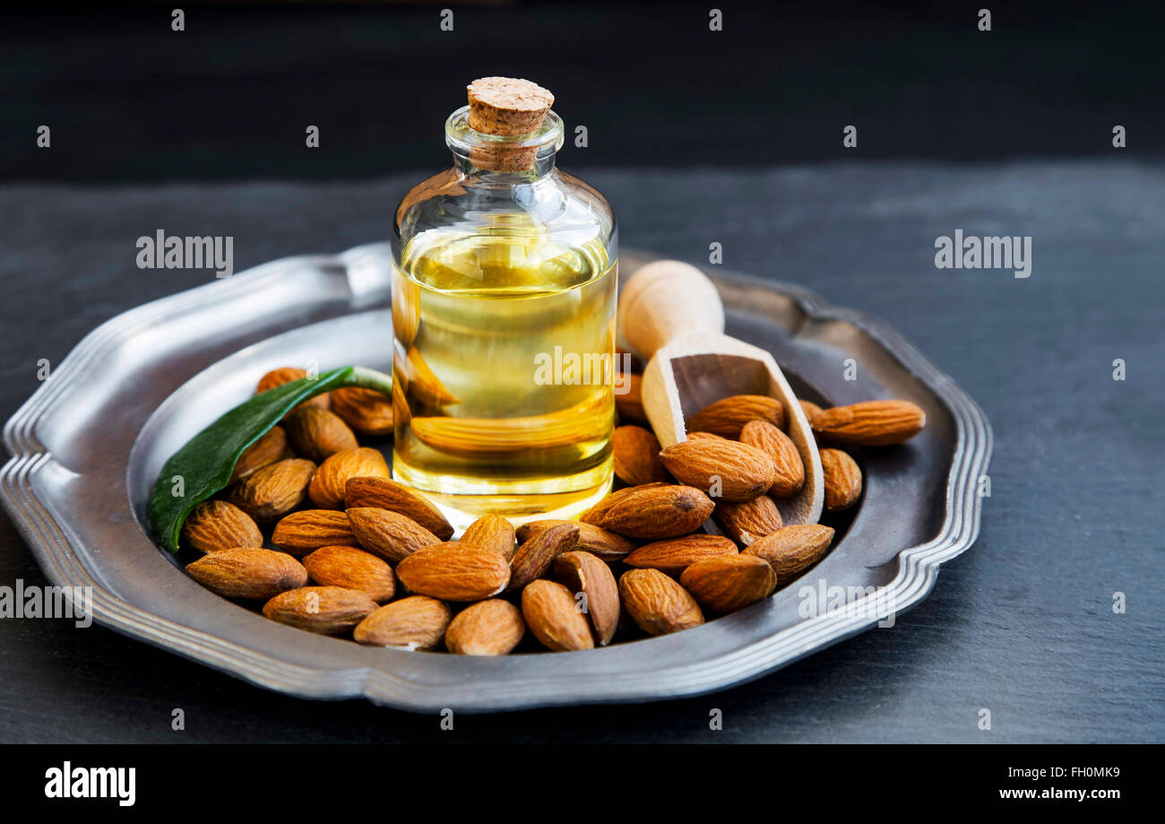 L'huile d'amande en bouteille transparente avec les amandes, l'huile de noix en bonne santé Banque D'Images