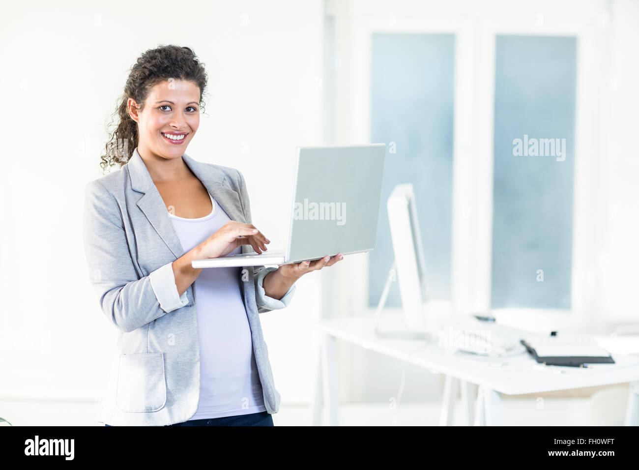 Portrait of pregnant businesswoman using laptop Banque D'Images