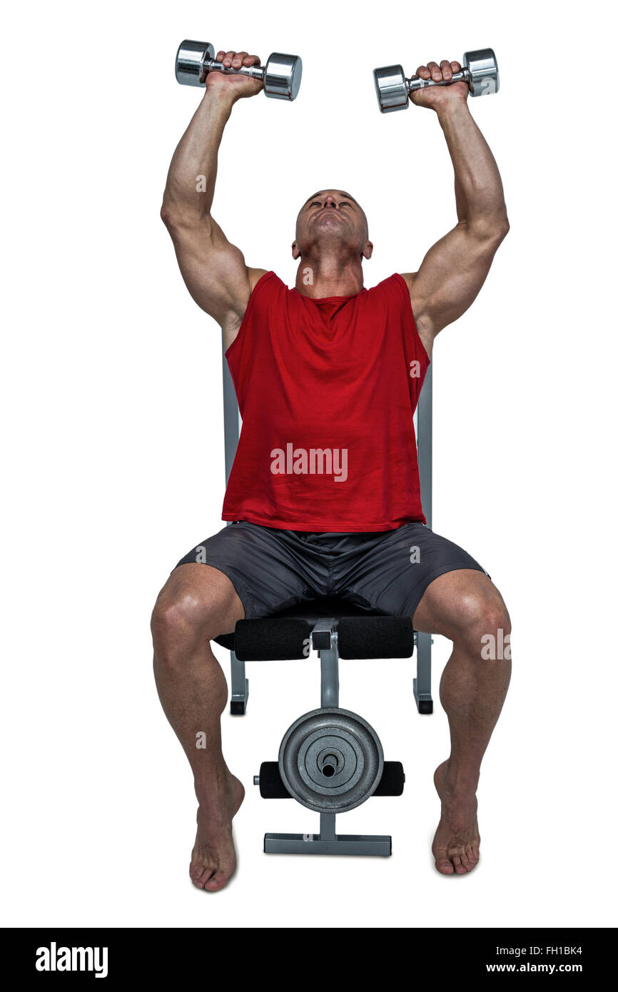 Man lifting dumbbells sain tout en étant assis sur le banc de muscu Banque D'Images