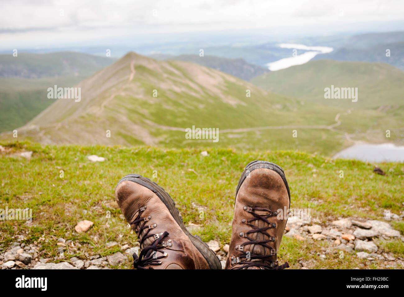 À la recherche de rouge Tarn au-delà de bottes de randonnée de hiker resting on Helvellyn, Lake District, Cumbria, Angleterre, Royaume-Uni Banque D'Images