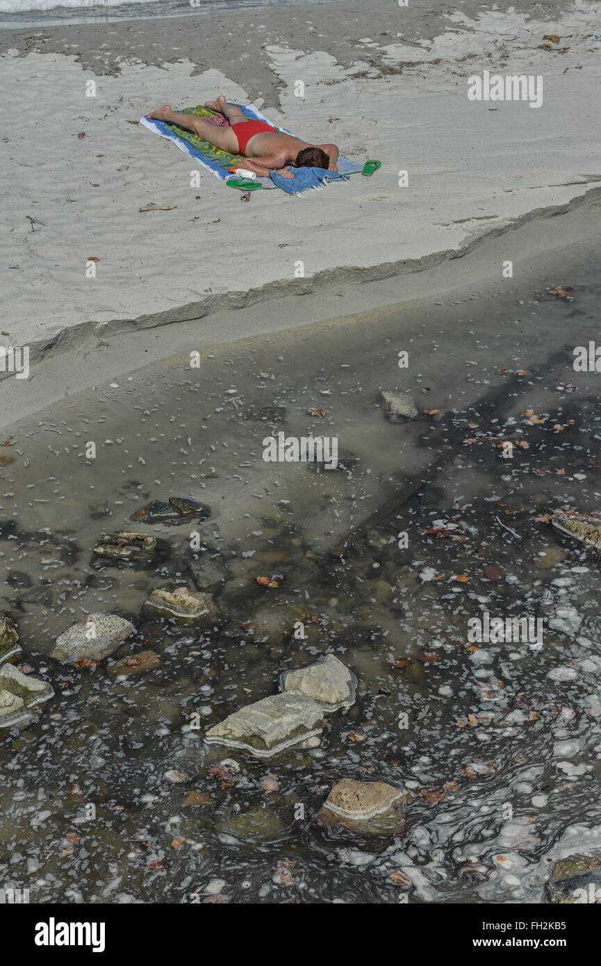 Sur une plage polluée Sunbather Banque D'Images