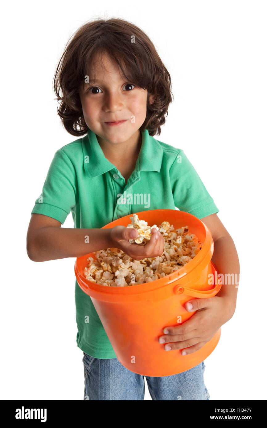 Petit garçon gourmand avec un grand seau orange sur fond blanc avec du maïs soufflé Banque D'Images