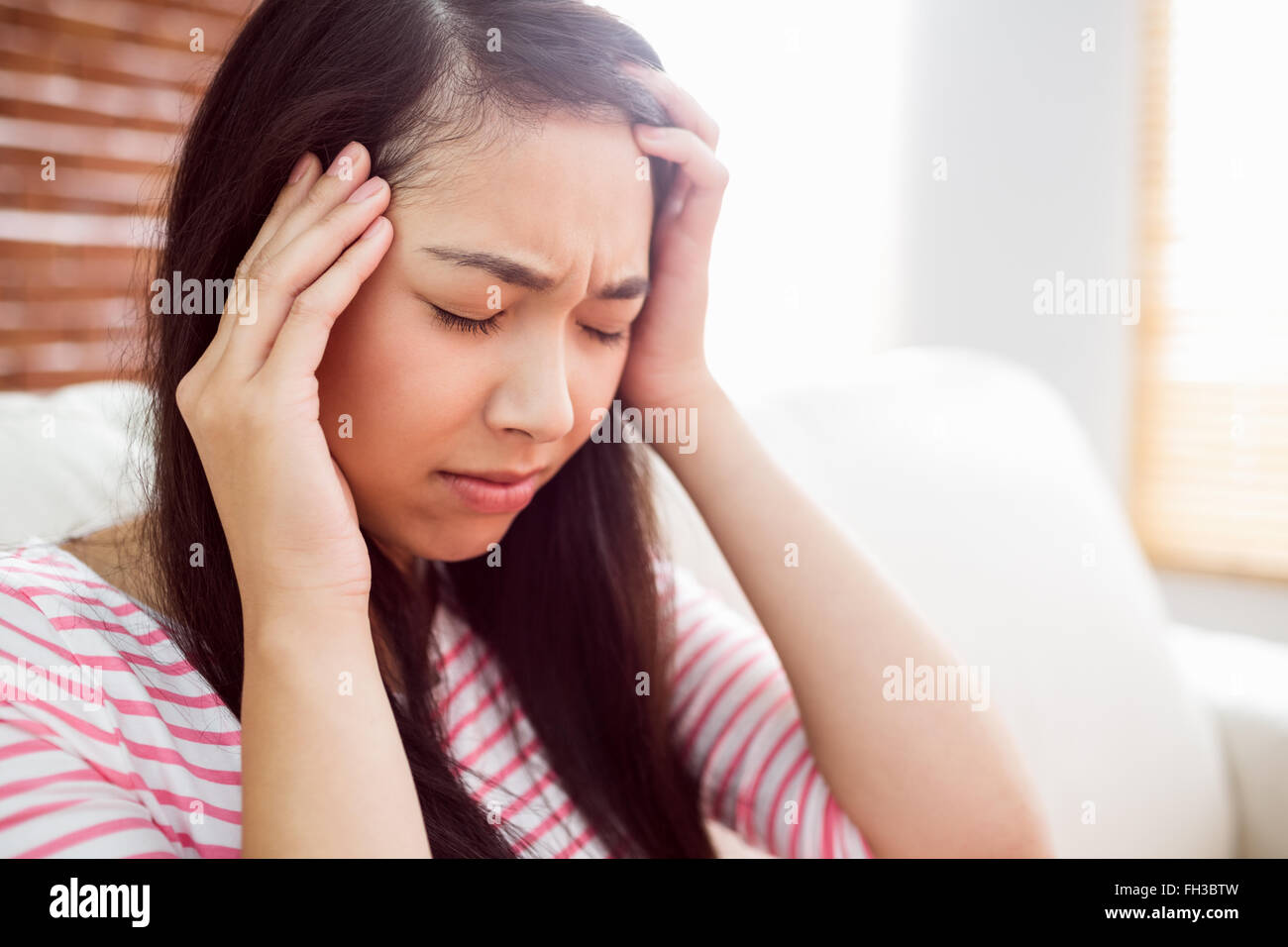 Asian woman getting maux on couch Banque D'Images