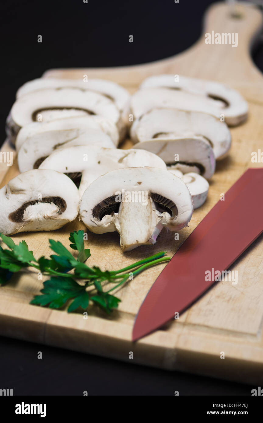 Champignons crus sur la planche à découper sur fond noir Banque D'Images